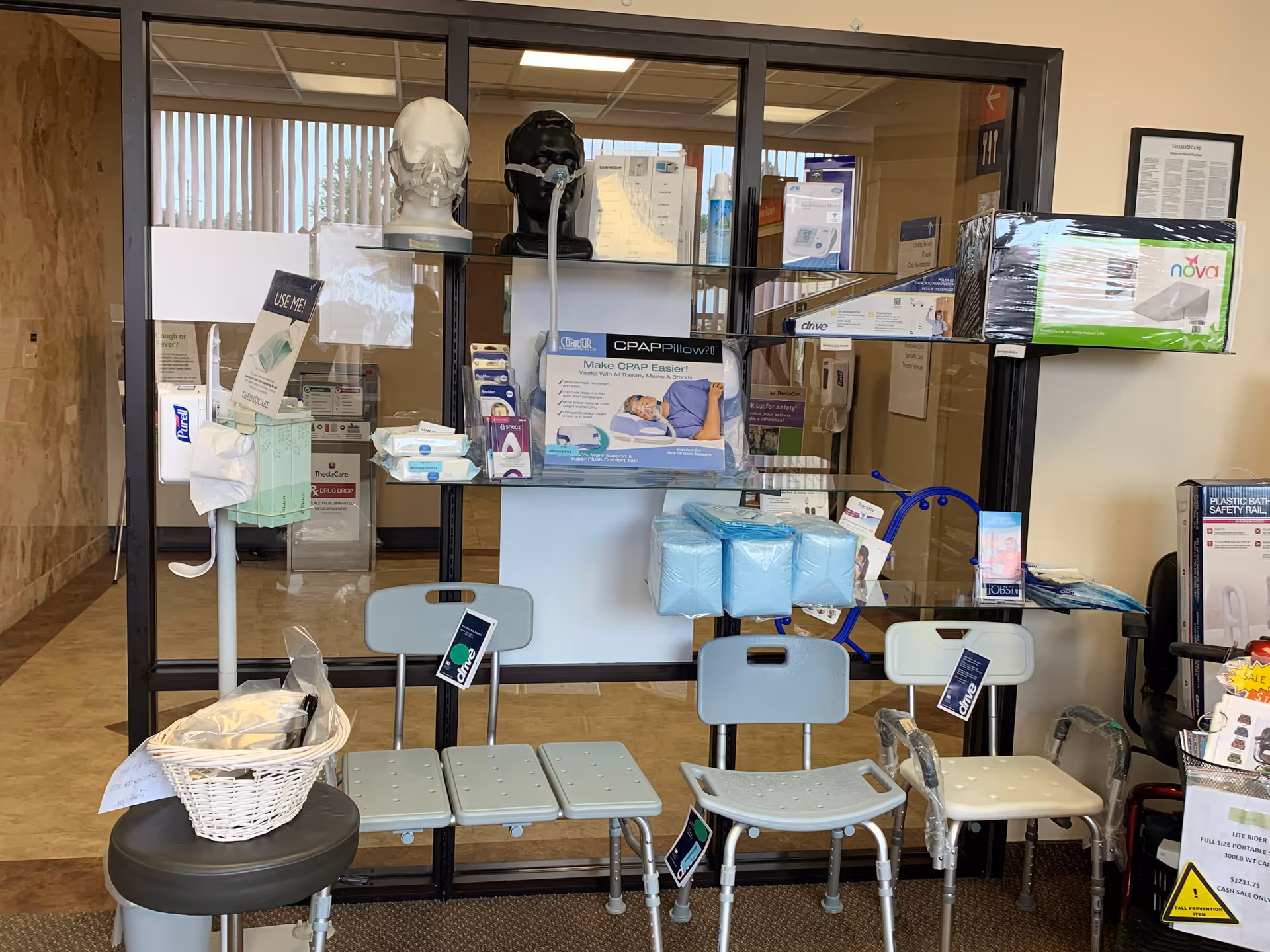 Medical supply display behind glass with chairs and CPAP equipment in a waiting area.