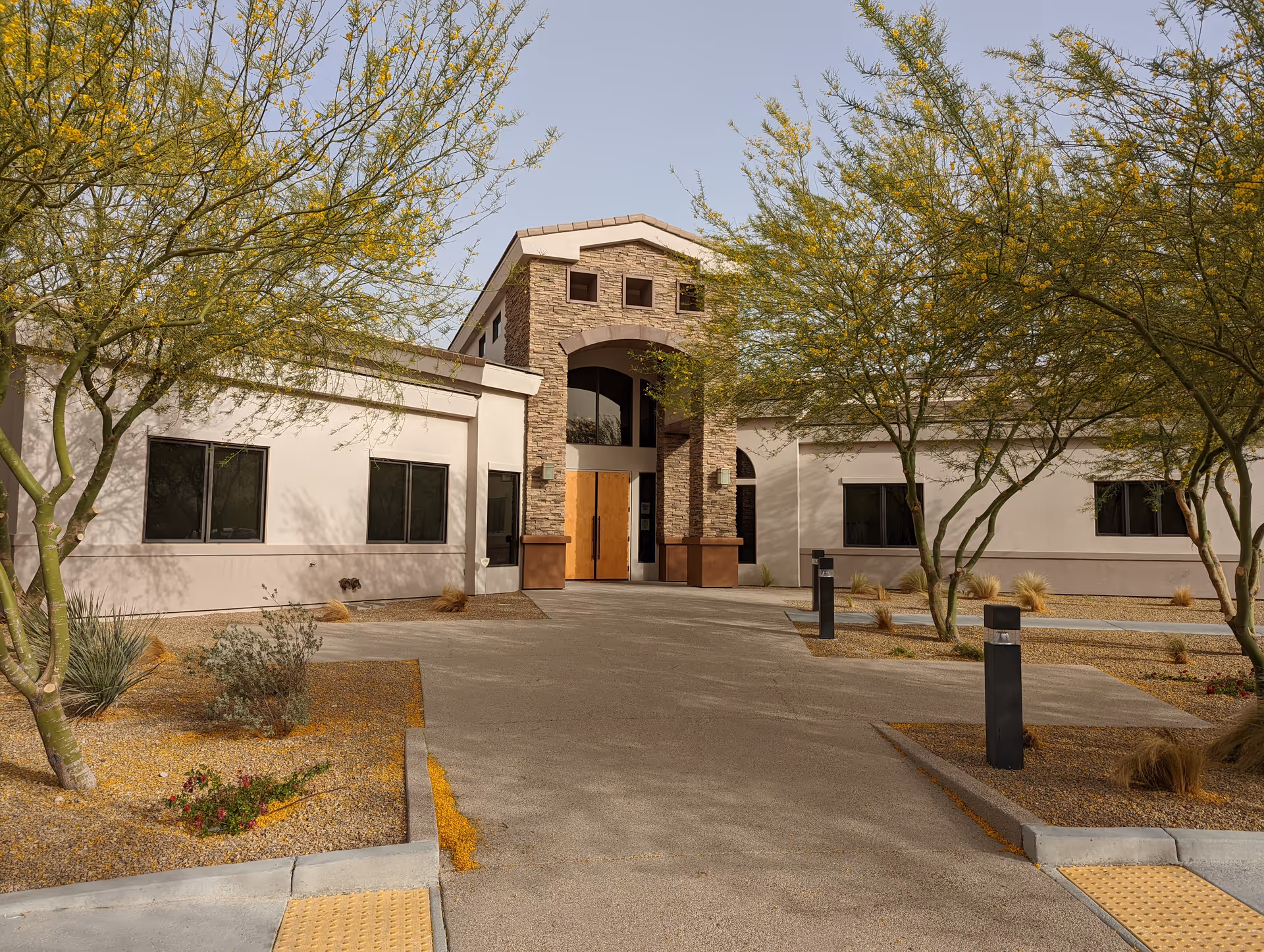 Front view of Infinity Hospice Care building with stone arch entrance and desert landscaping