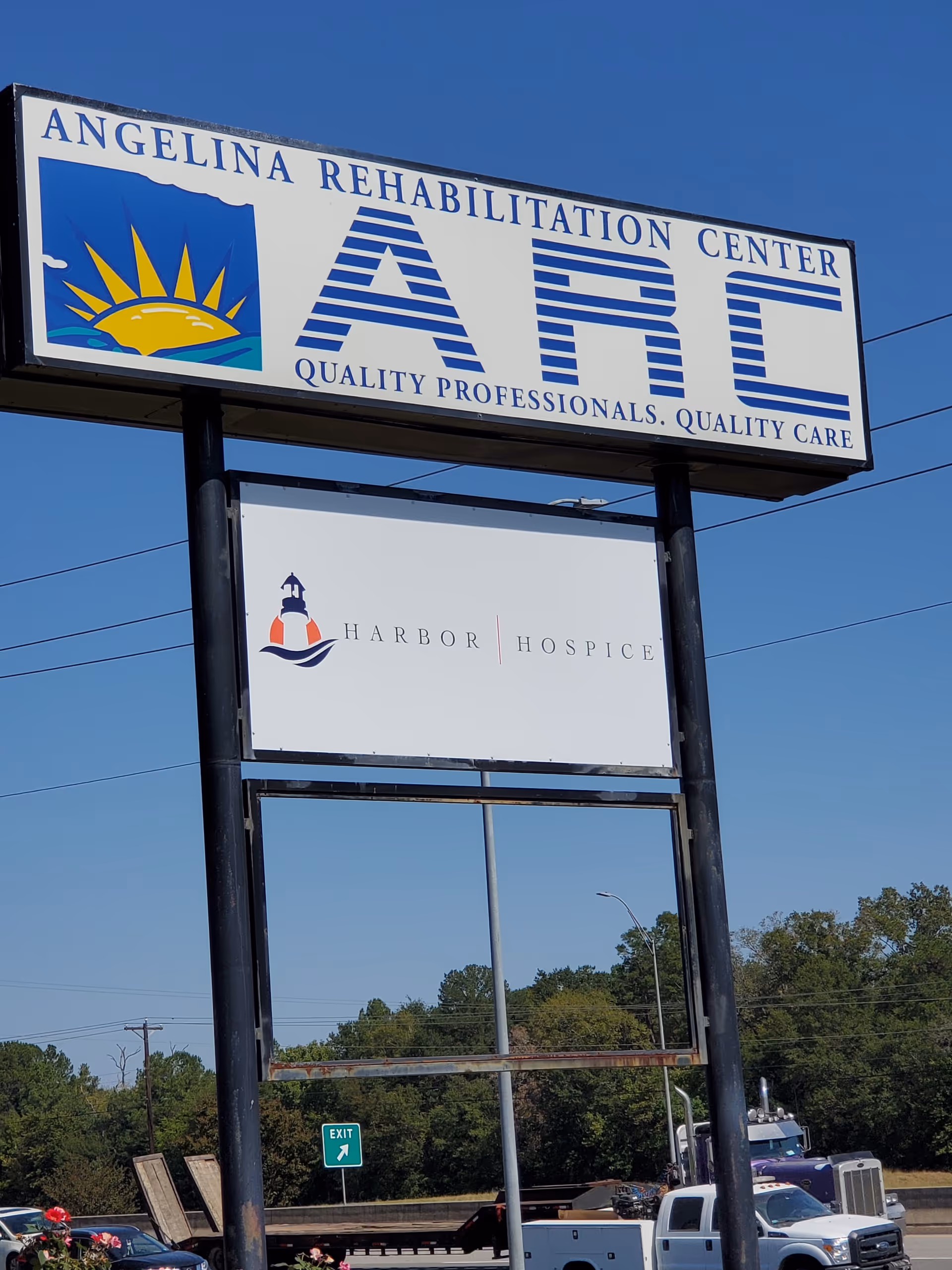 Tall outdoor sign for Angelina Rehabilitation Center with Harbor Hospice logos against a blue sky.