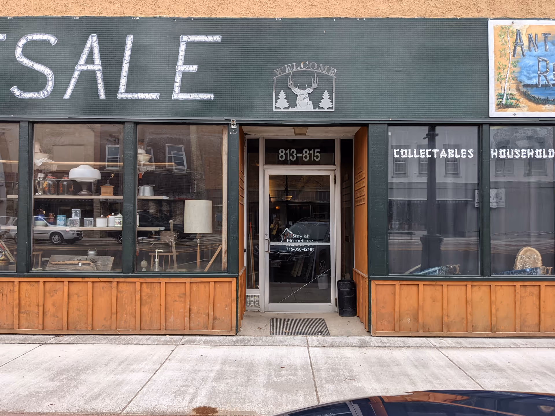 Exterior storefront with large SALE sign, windows display items, central door, address 813-815.