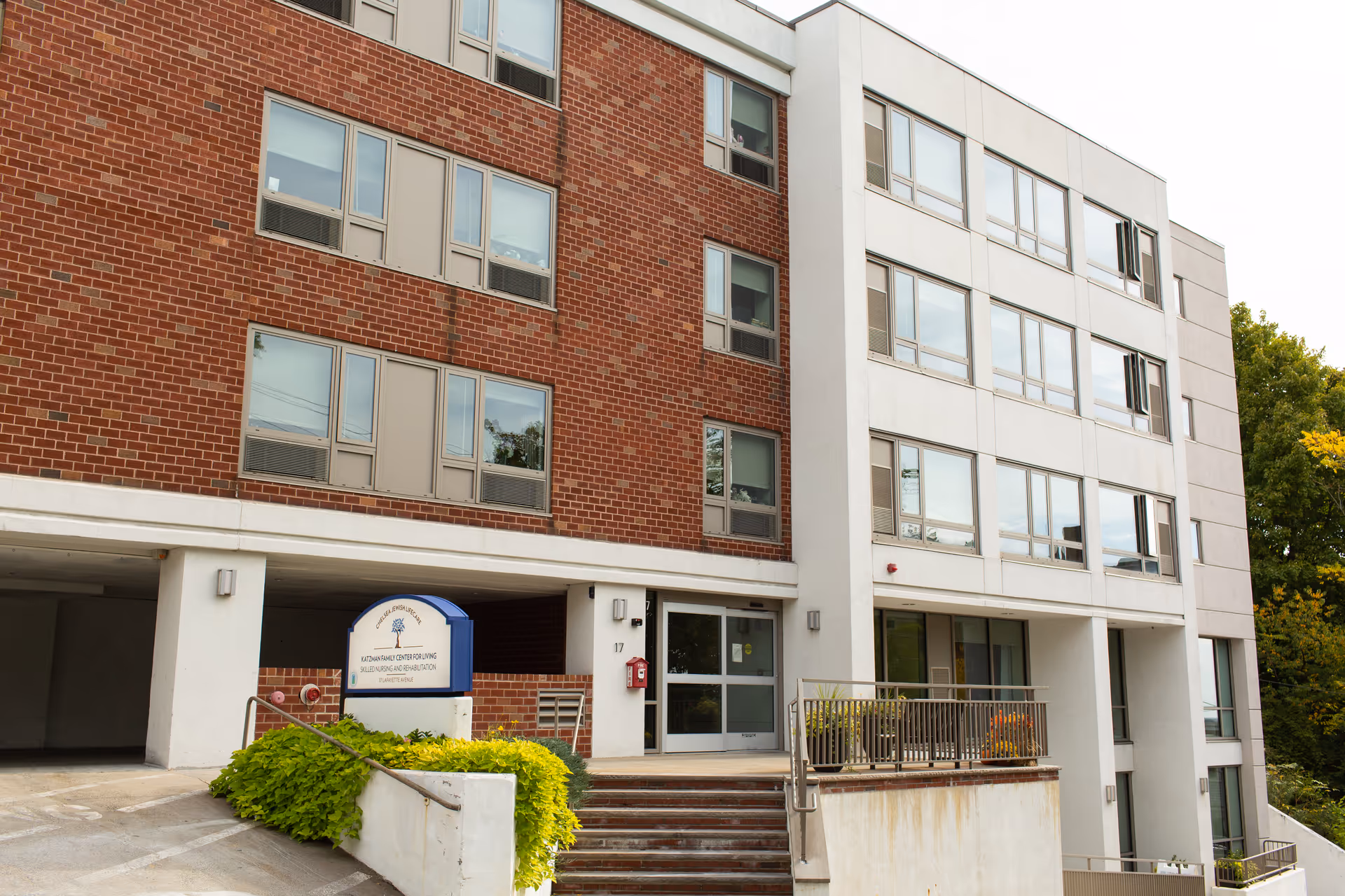 Exterior view of Katzman Family Center for Living building with entrance, sign, and stairs.