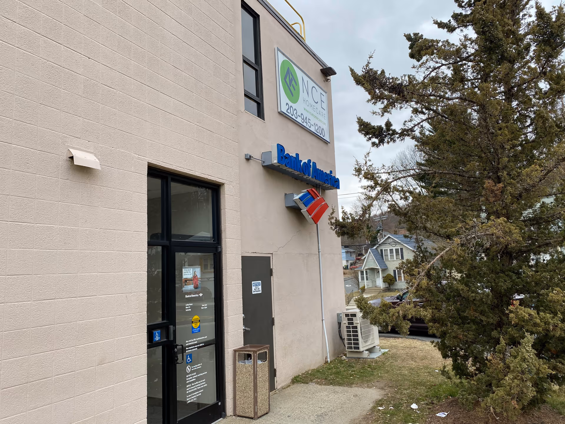 Exterior view of NCE Homecare building with sign, flag, and nearby trees.