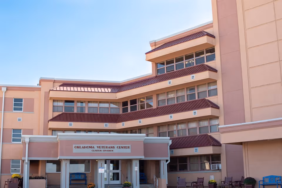 Exterior view of a pink Oklahoma Veterans Center building with a covered entrance.