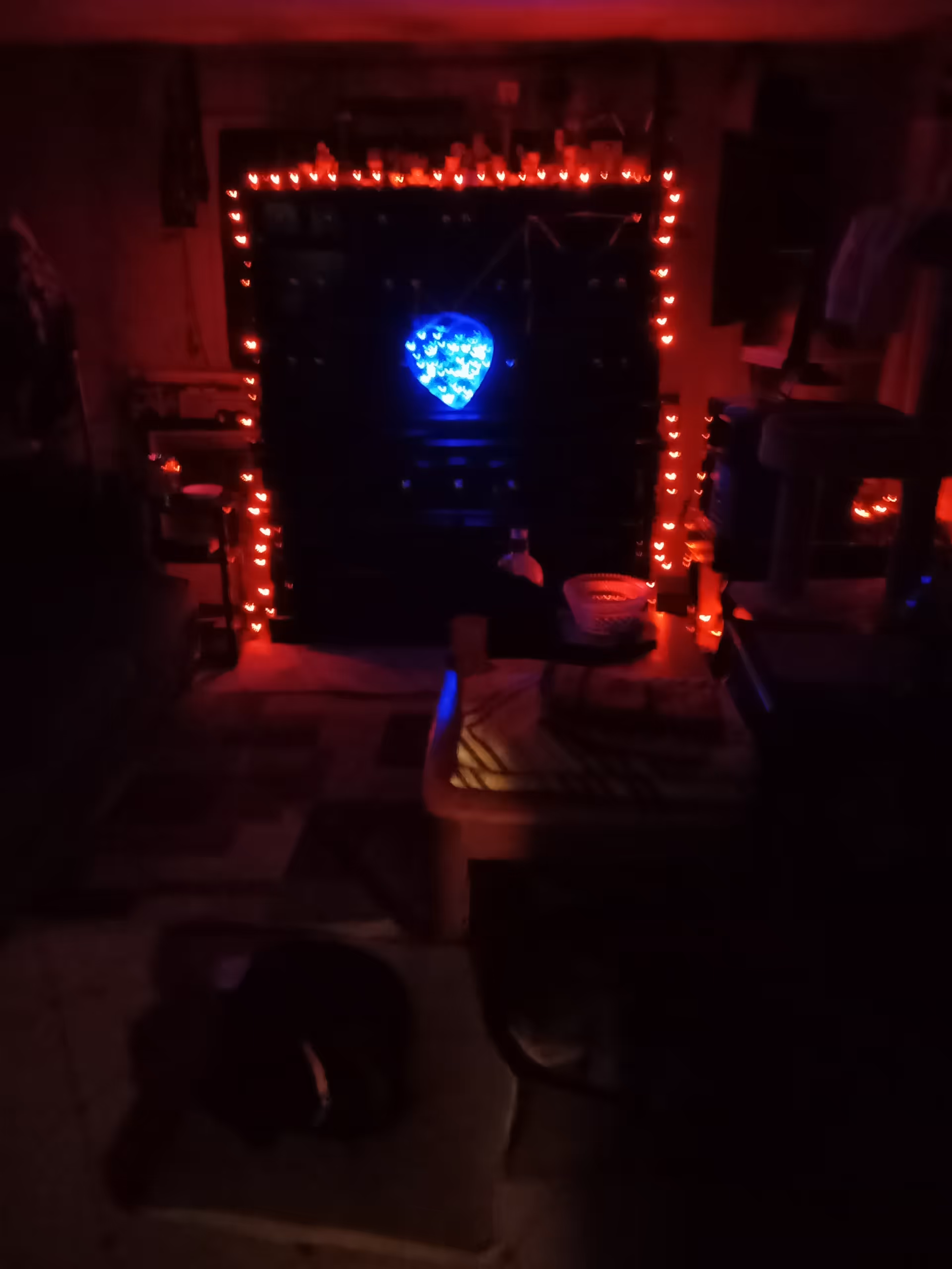 Dark interior with red string lights around a black cabinet and blue heart centerpiece.
