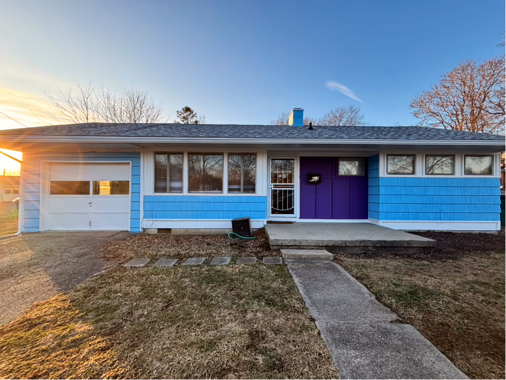 Blue single-story building with a purple front door and walkway to entrance.