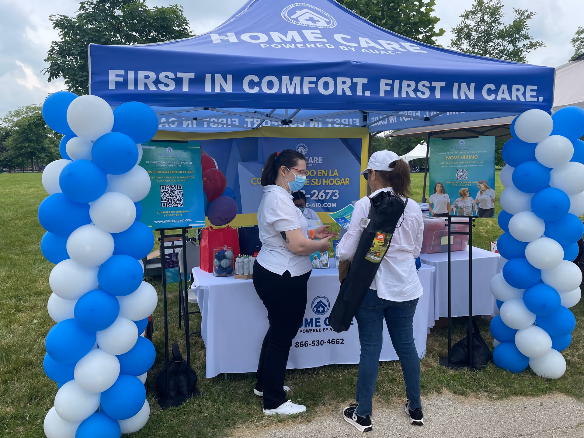Two staff members converse at a Home Care Arizona outdoor booth with balloons