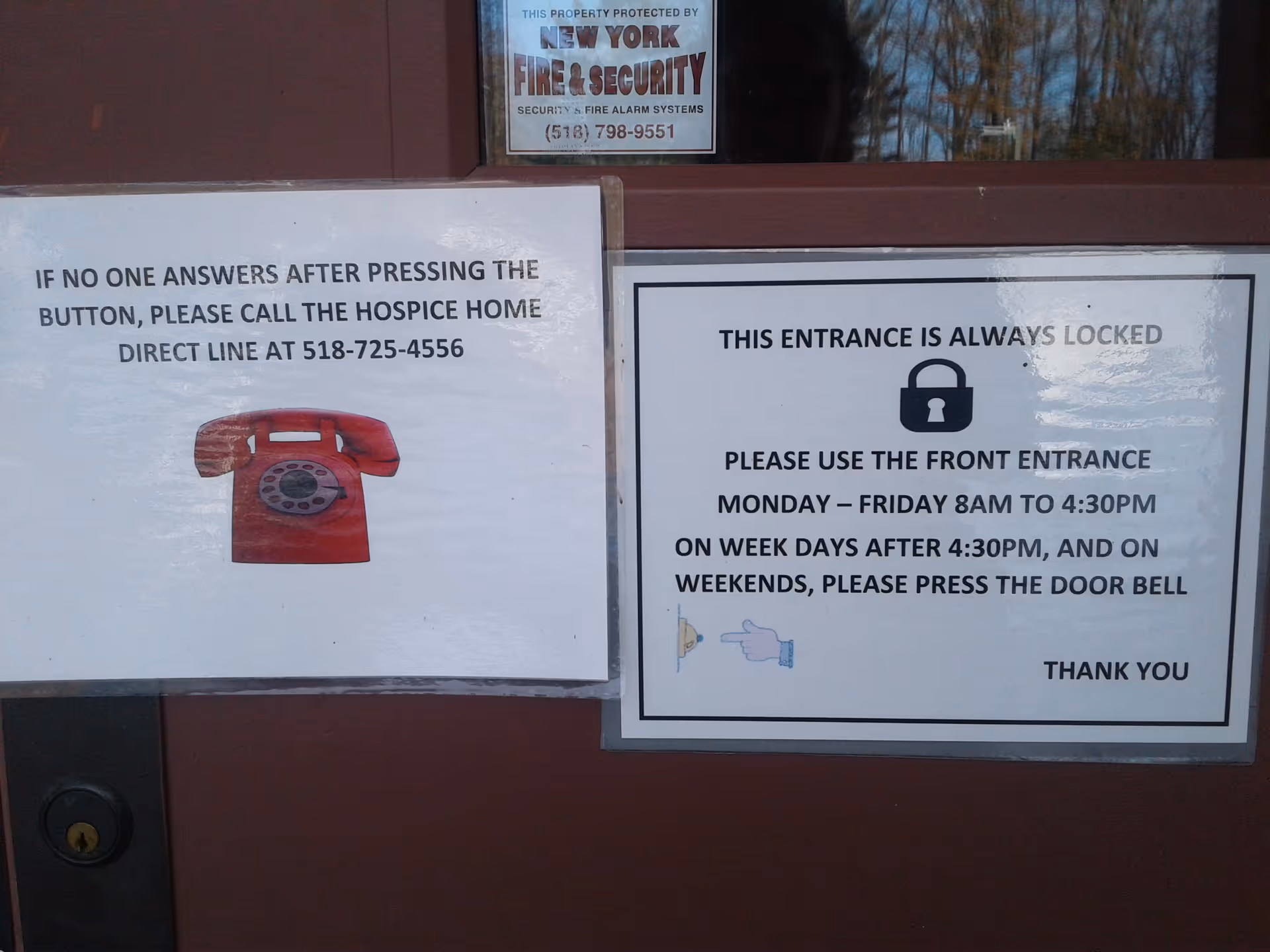 Front doorway with two signs, including a red telephone image on the left.