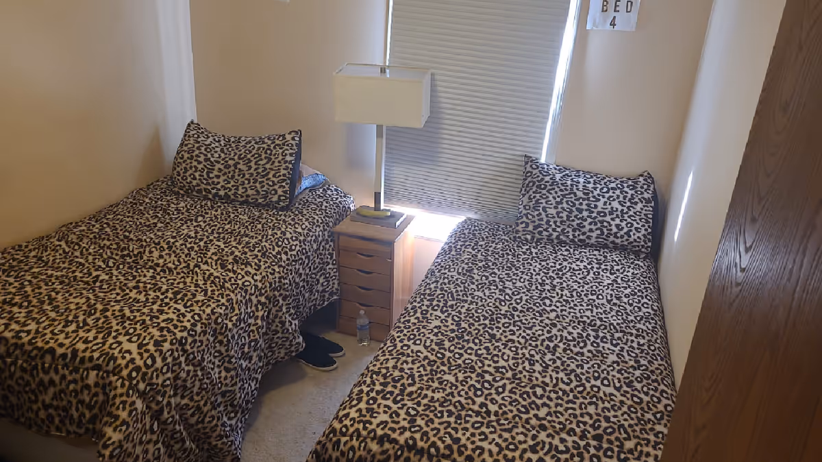 Two twin beds with leopard-print bedding in a small bedroom.