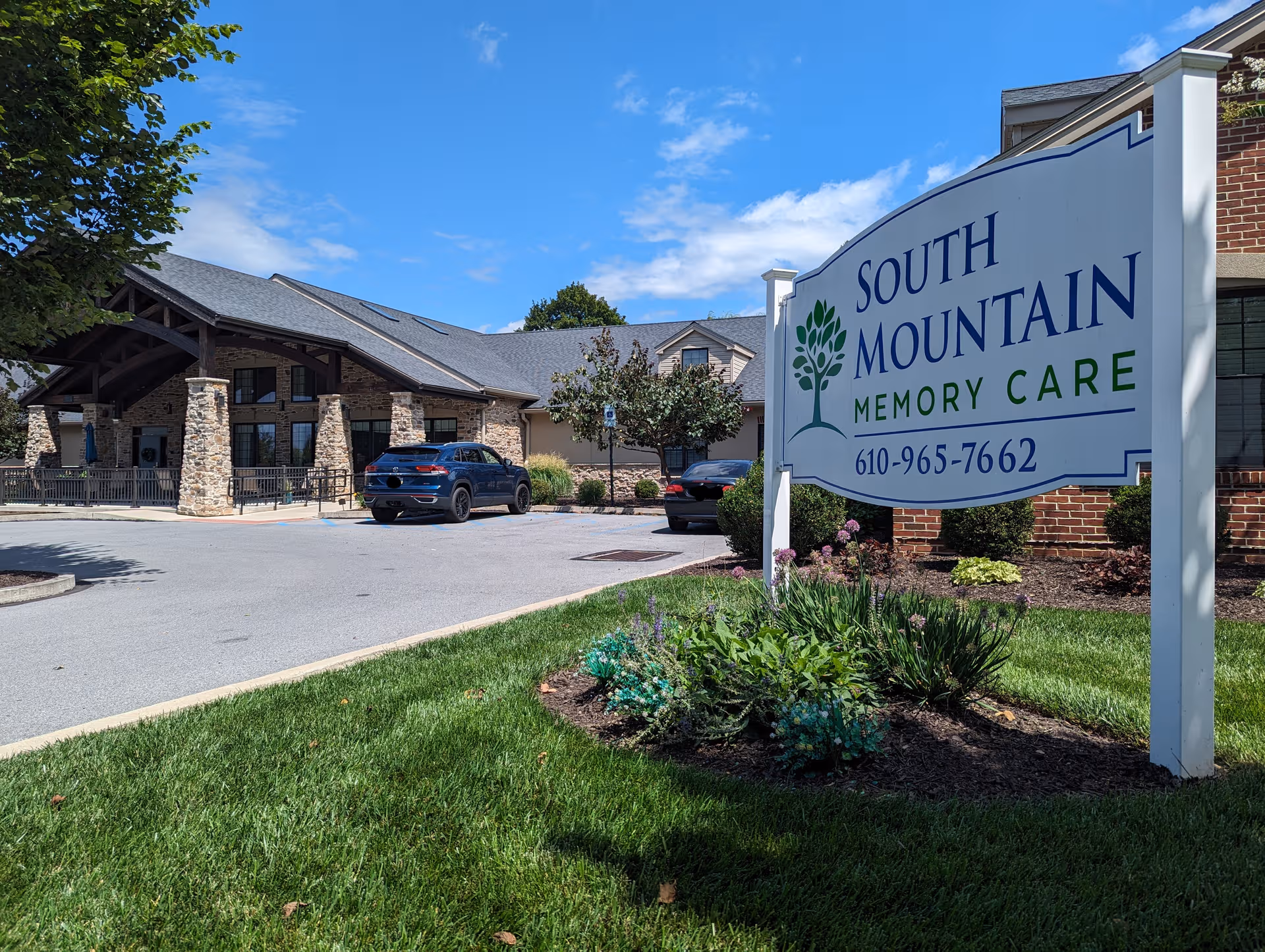 Exterior view of South Mountain Memory Care with sign, landscaping, and parked cars.