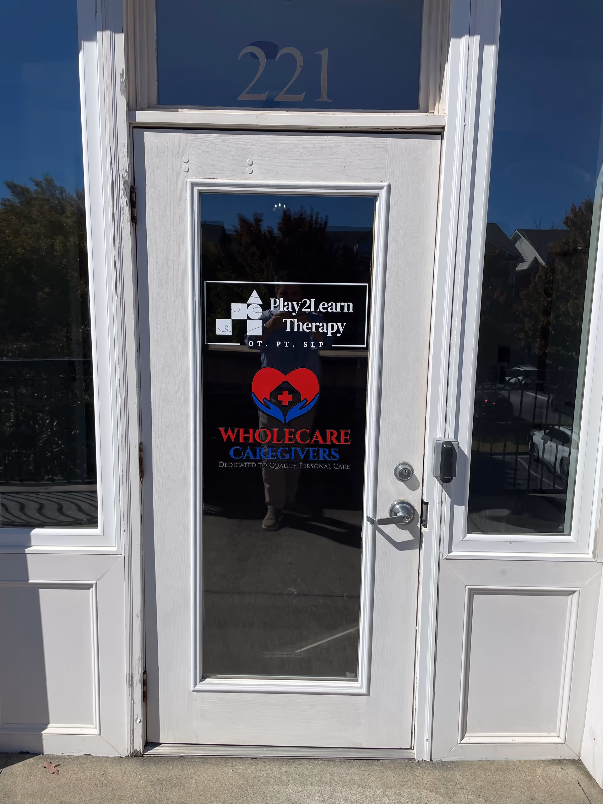White front door with Play2Learn Therapy and Wholecare Caregivers logos.