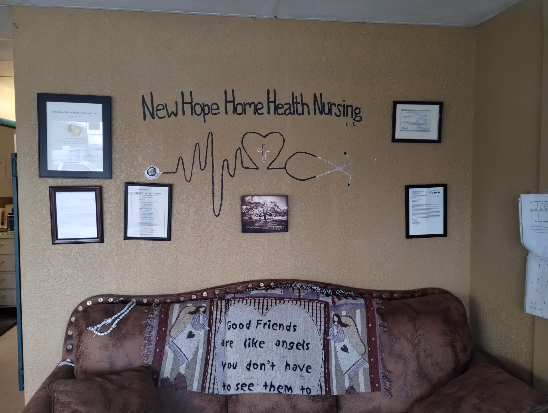 Brown sofa in tan-walled lounge with framed documents and New Hope Health mural.