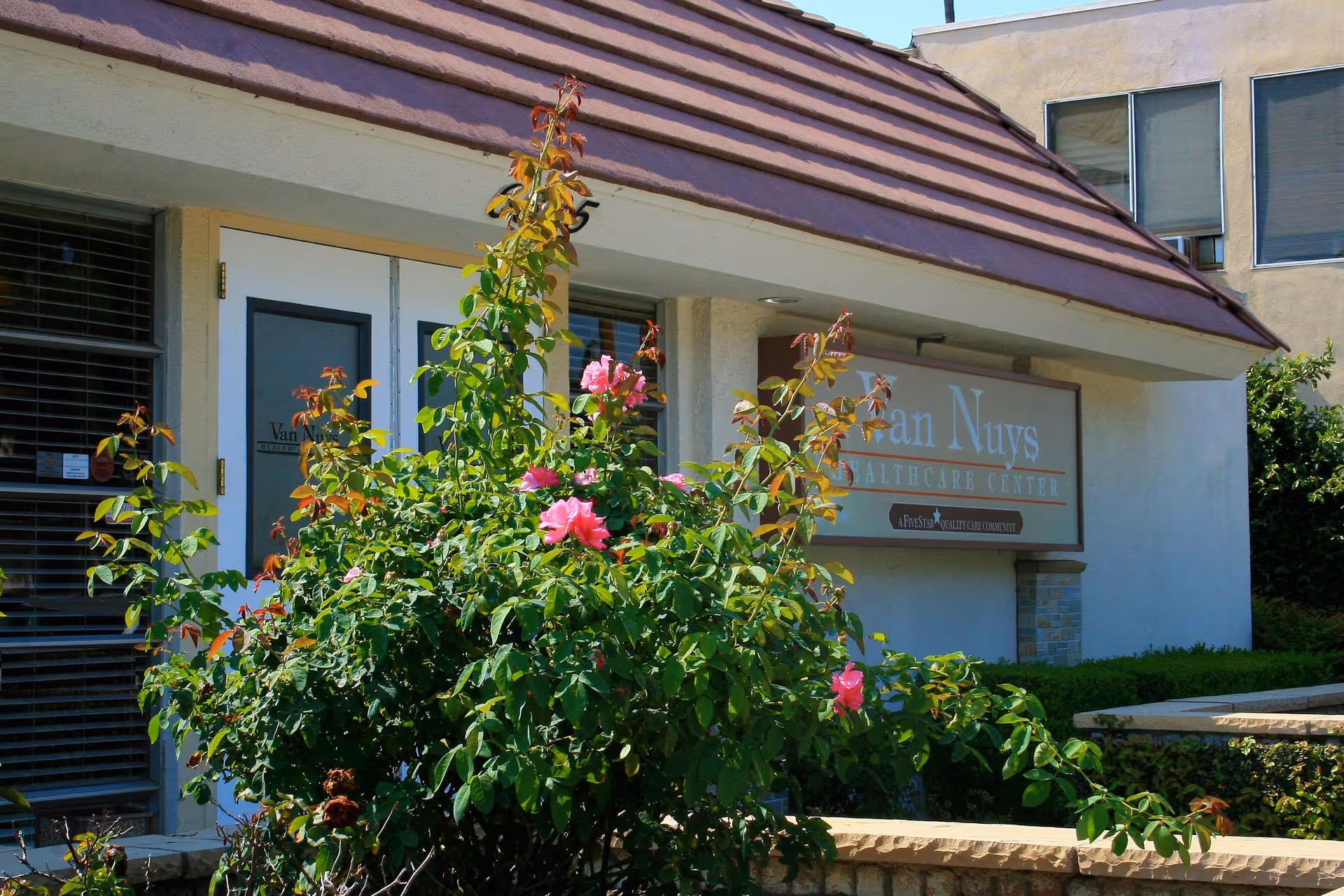 Exterior view of The Care Center on Hazeltine with flowering shrubs in the foreground.