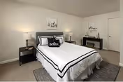 A neatly made bedroom with a queen bed, nightstands, lamps, and a dresser.