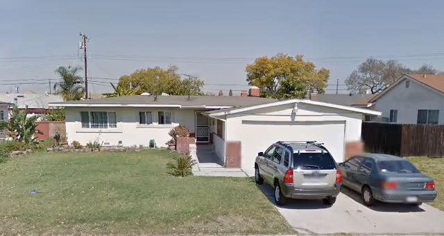 Front view of a single story senior care facility with a driveway and two parked cars.