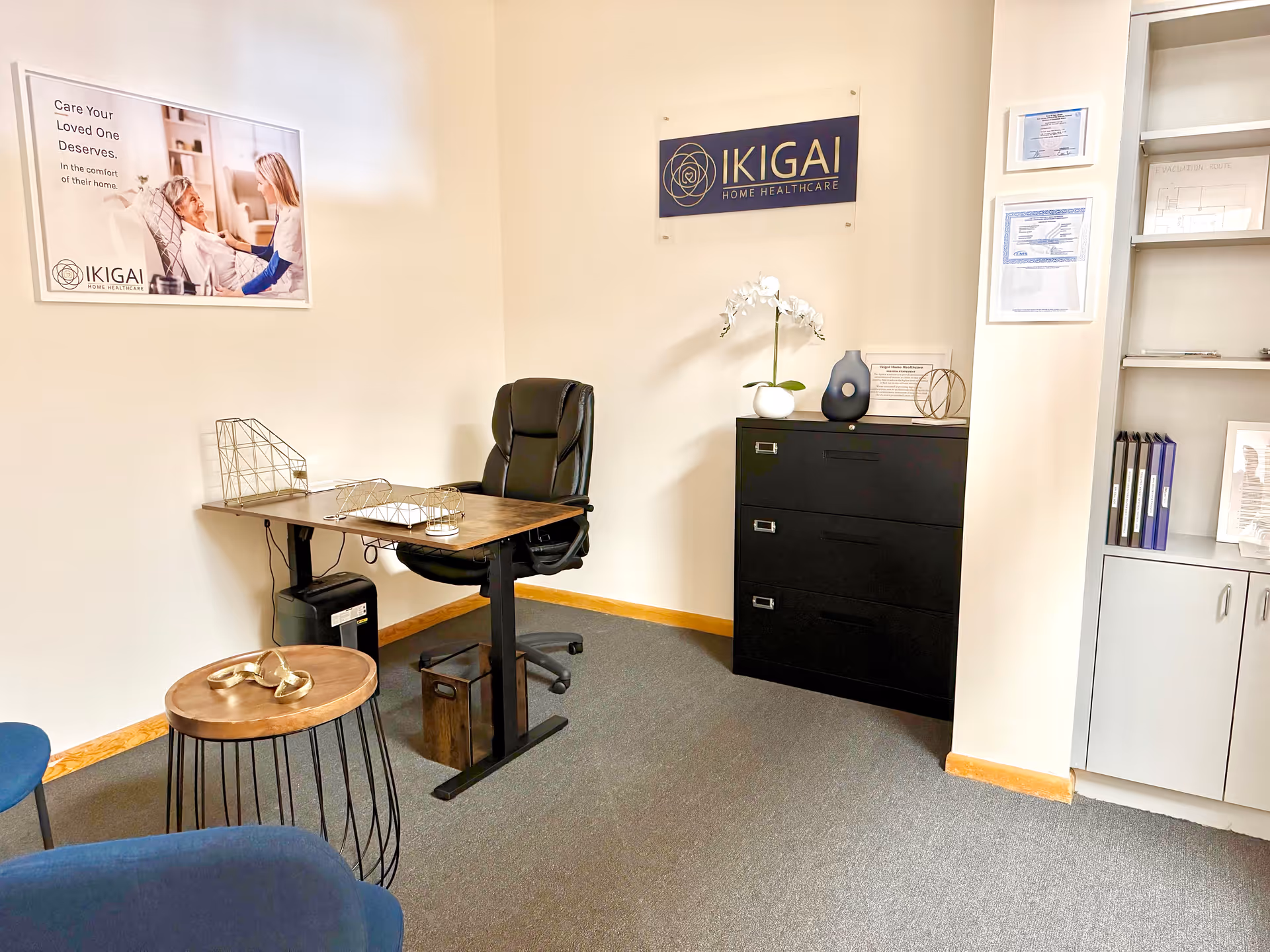 Office area with desk, chair, filing cabinet, and Ikigai Home Healthcare sign.