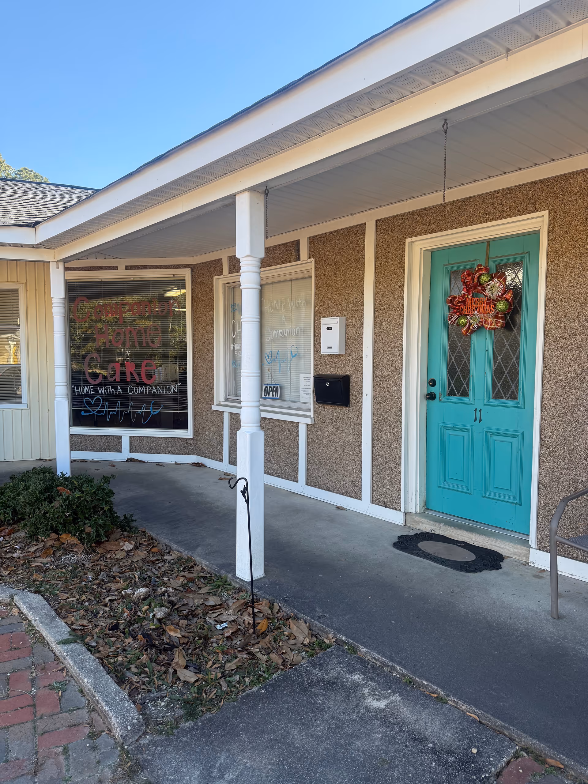 Exterior view of a building entrance with turquoise door and wreath, Companion Home Care sign visible.