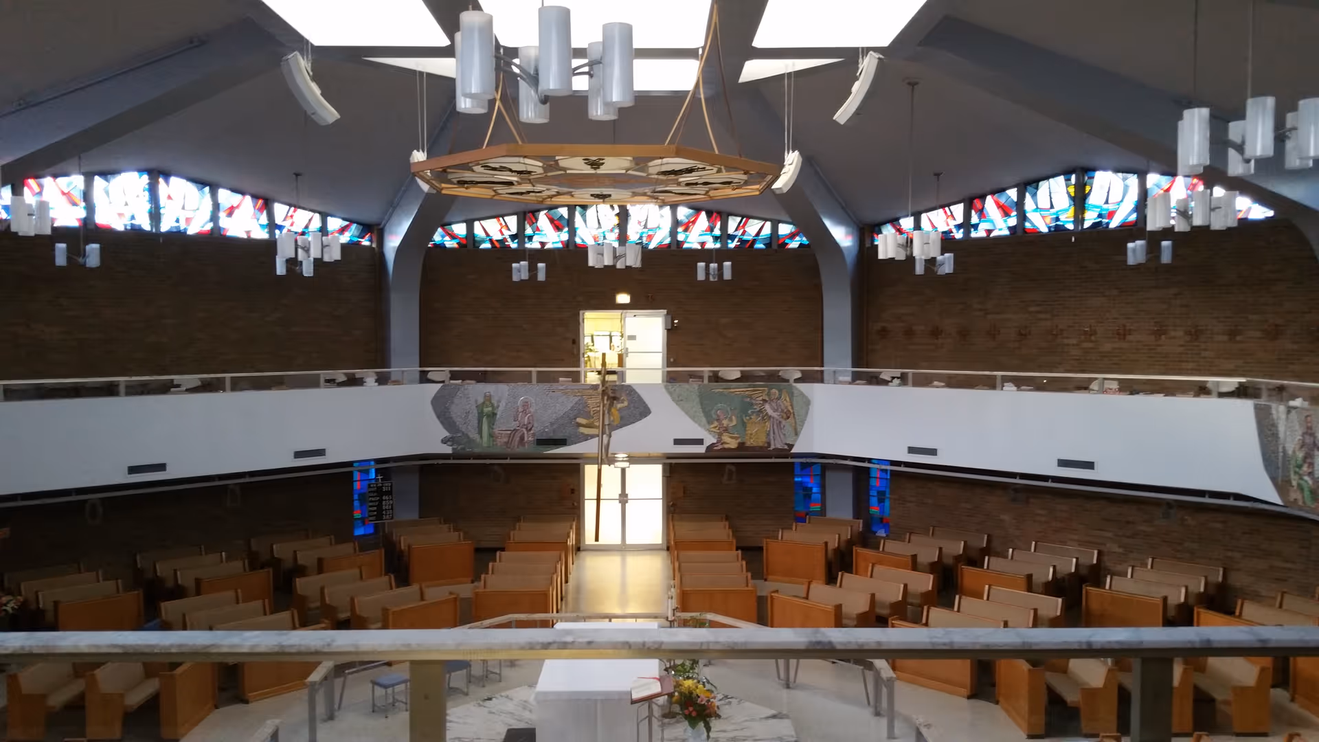 Interior of Our Lady of Angels Ret Home chapel with pews, stained glass, brick walls.