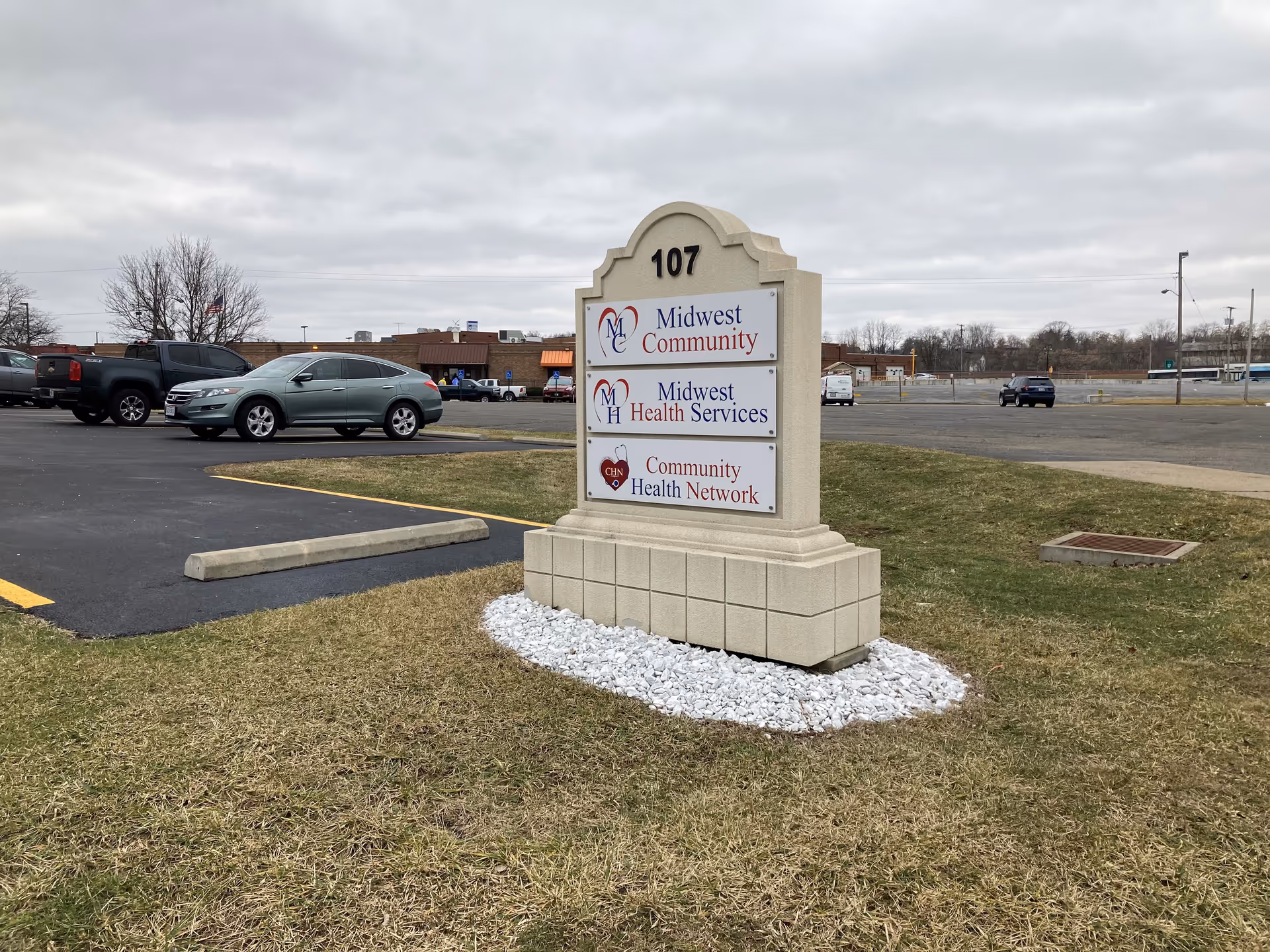 Outdoor scene of a stone sign for Midwest Community and Midwest Health Services.