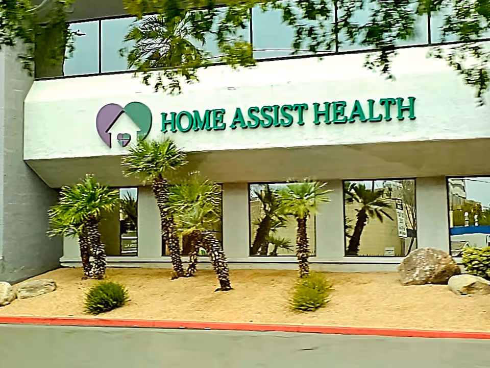 Home Assist Health building exterior with sign and palm trees in front.