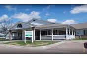 Single story white care home with a covered front porch and a sign by the entrance.
