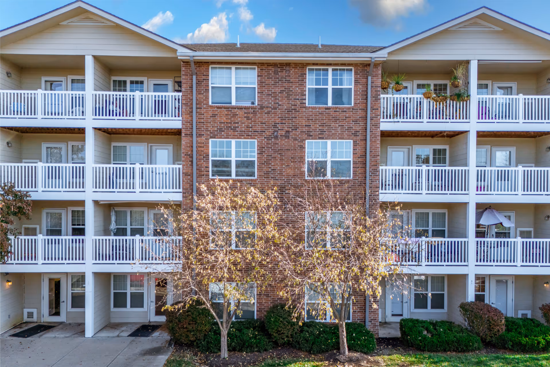 Exterior view of a Rosewood Place senior living building with brick center and white balconies.