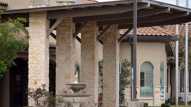Exterior view of The Medical Resort at Pearland with stone columns and fountain under covered walkway