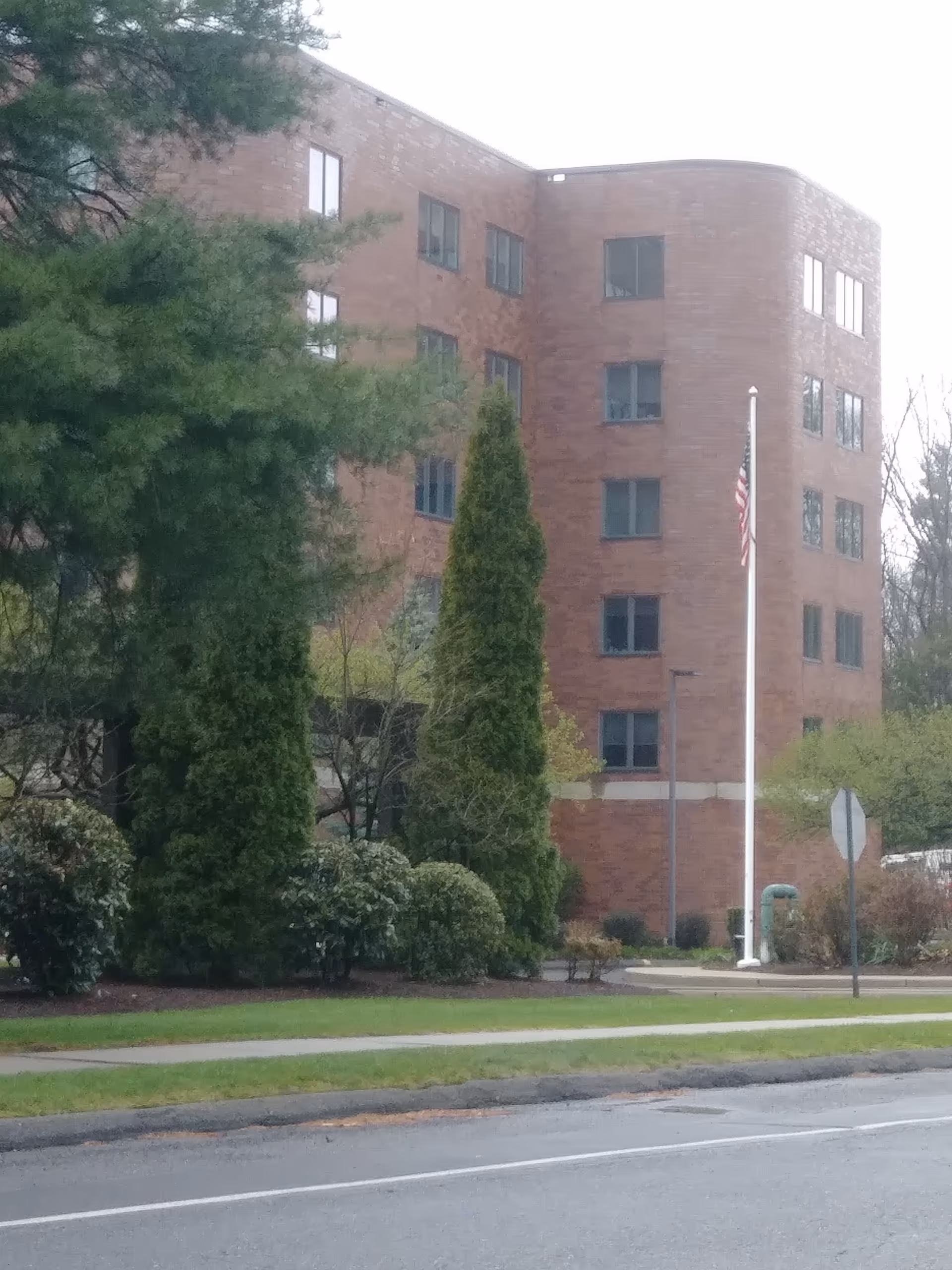 Exterior view of a brick Whitney Center building with trees and an American flag.