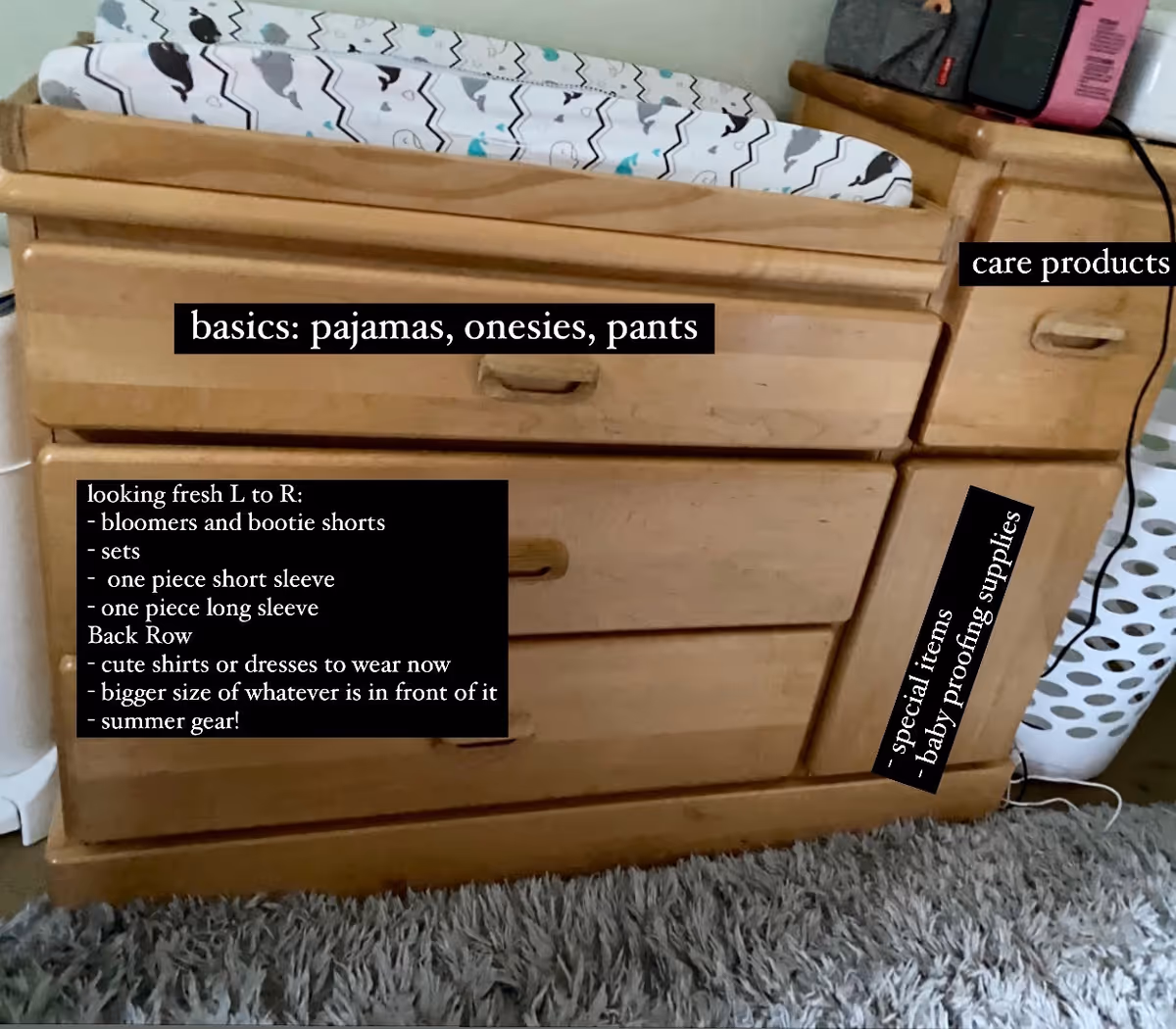 Wooden dresser with drawers and black label text describing clothing and baby items.
