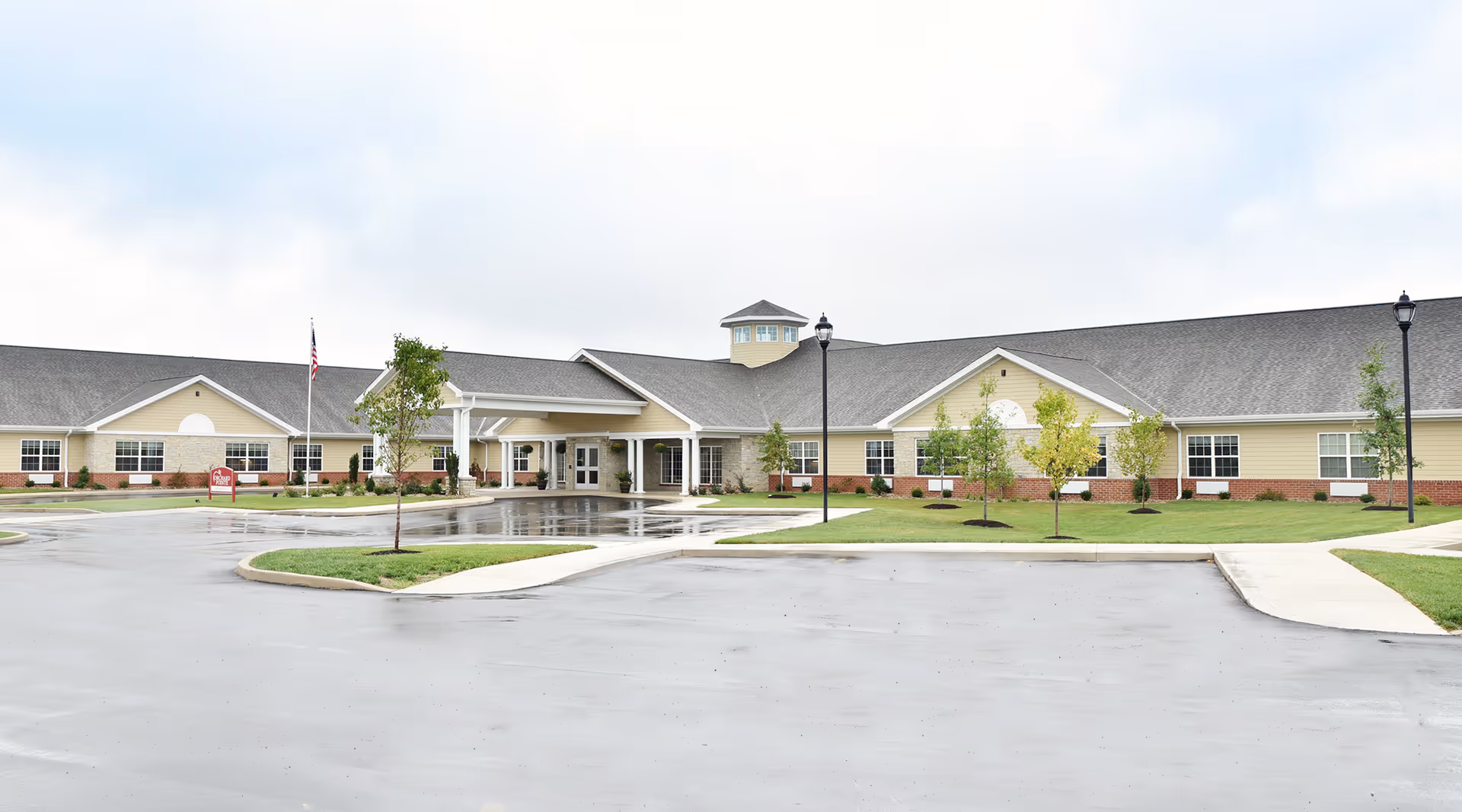 Exterior view of a single-story senior living campus with a central entrance and manicured landscaping.