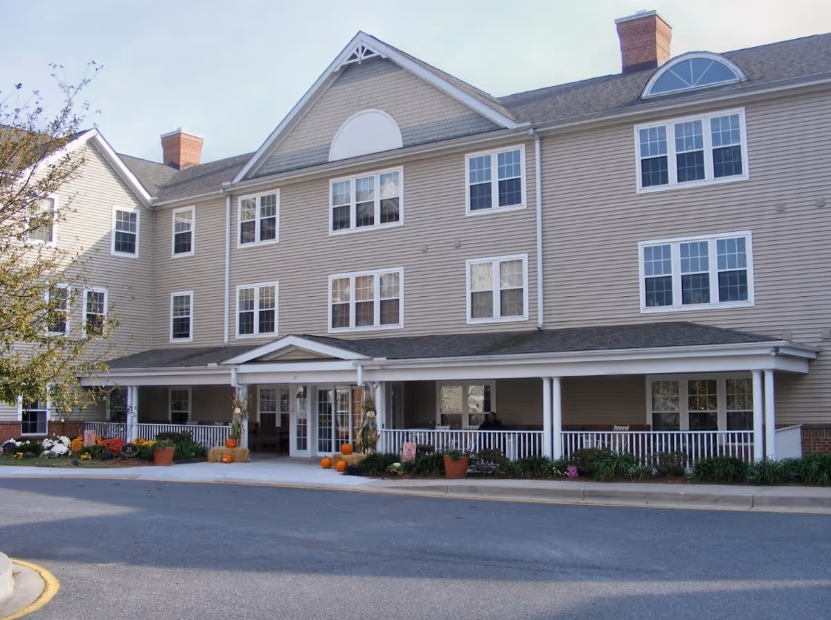 Front exterior of Whispering Meadows Senior Care Homes, a beige three-story building with pumpkins.