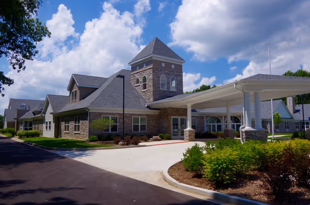 Front view of a stone-clad senior living center with a covered entrance driveway.