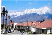 Exterior view of Stroud Health Care Center South with red-roofed buildings, palm trees, and mountains.