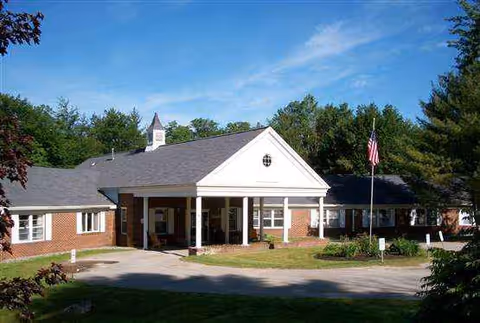 One-story brick senior living center with white columns, a portico entrance, and an American flag.