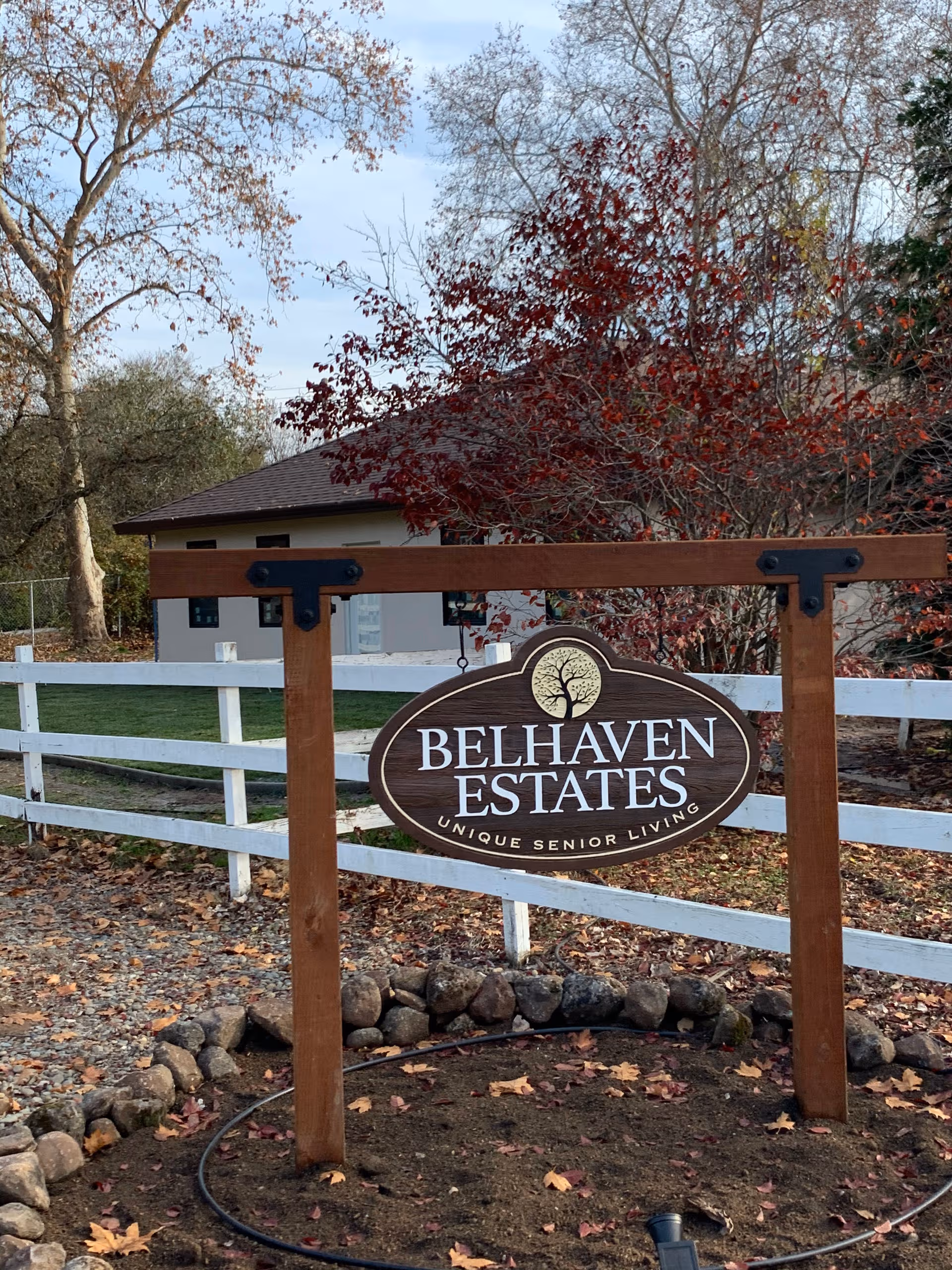 Autumn leaves surround the Belhaven Estates sign mounted on a wooden frame