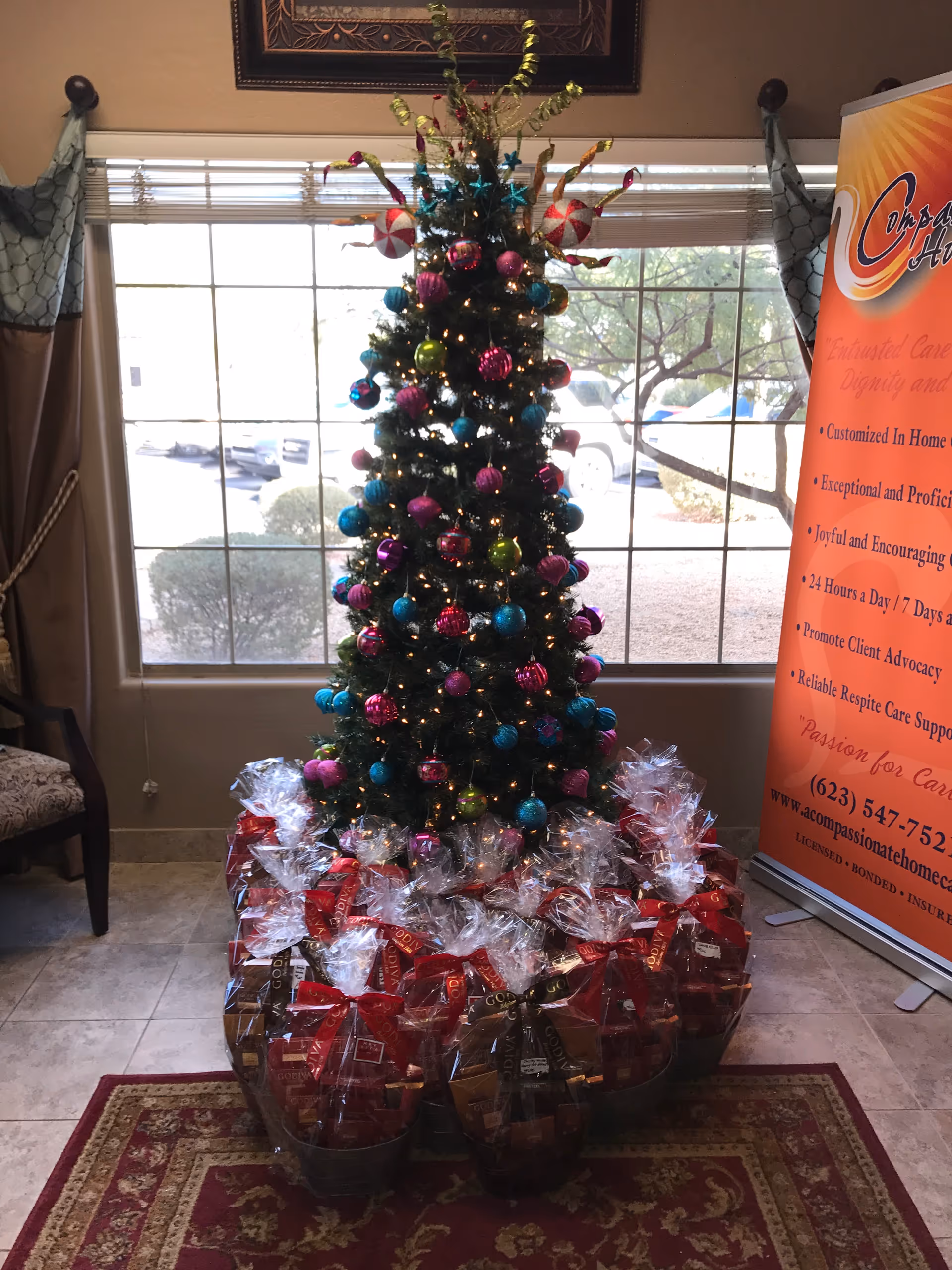 Decorated Christmas tree with gift baskets in a warmly lit lobby.