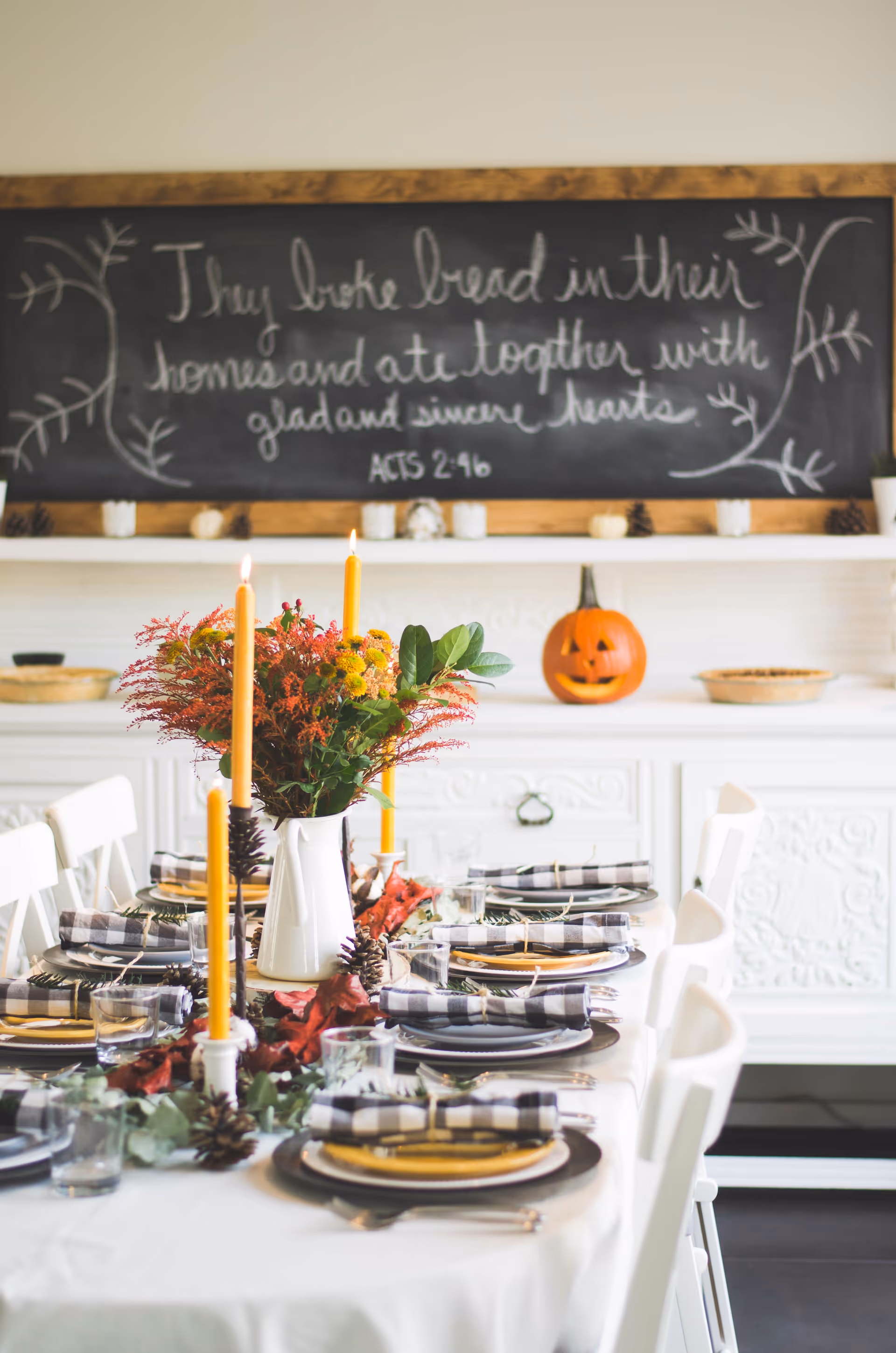 Seasonal dining room table set with candles, pumpkins, and a floral centerpiece.