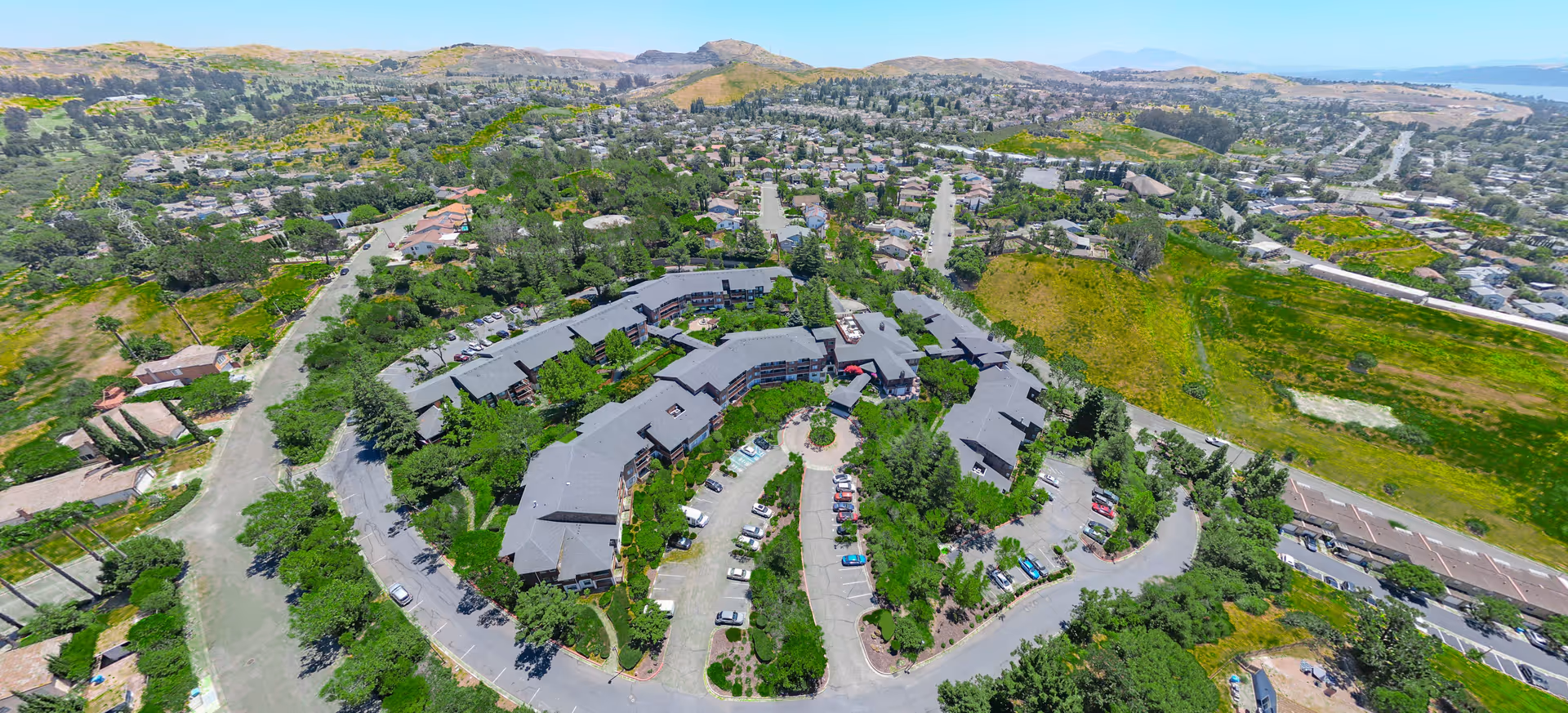 Aerial view of Cogir of Vallejo Hills Senior Living campus with winding roads and greenery.