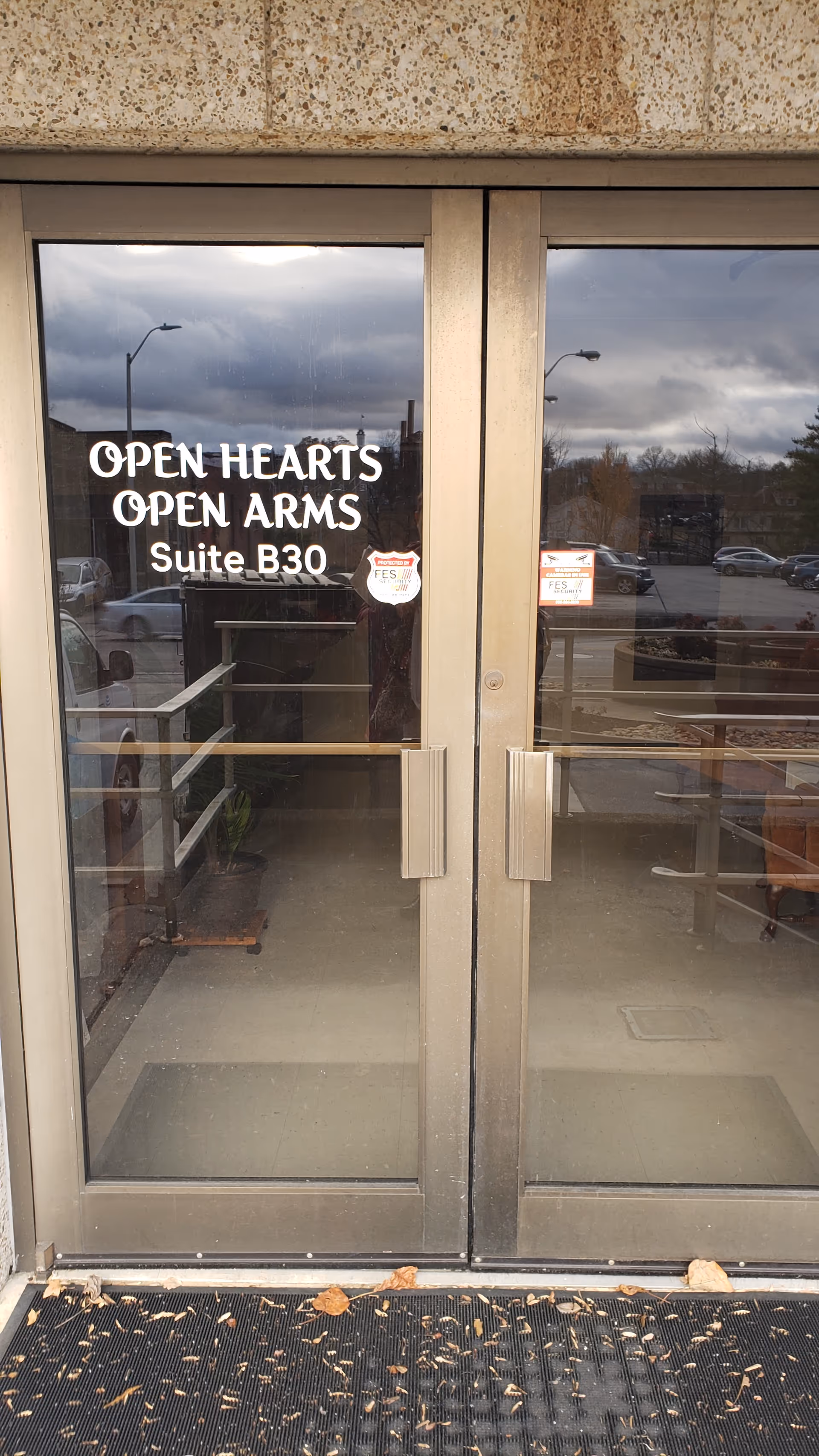 Glass double doors display the Open Hearts Open Arms entrance with Suite B30 signage.