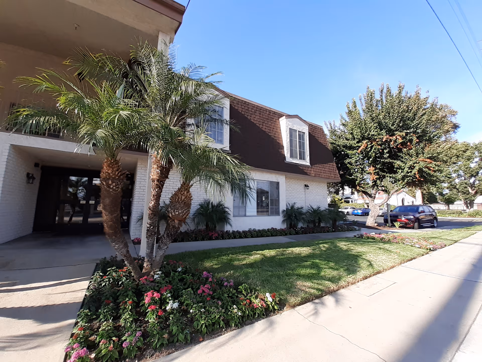 Atria Covina exterior with white brick, palm trees, and a landscaped entrance