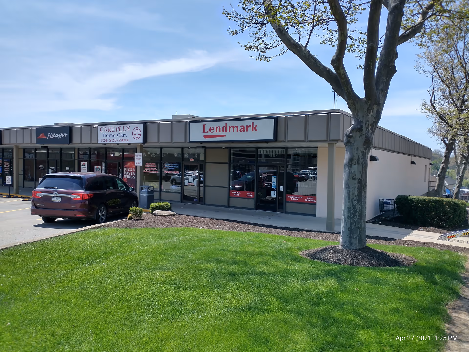 Exterior of a strip mall with Care Plus Home Care and Lendmark storefronts.