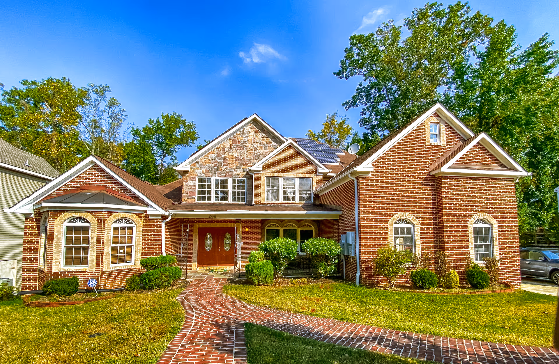 Front exterior view of Bonhill senior living building with brick walkway and lush trees.