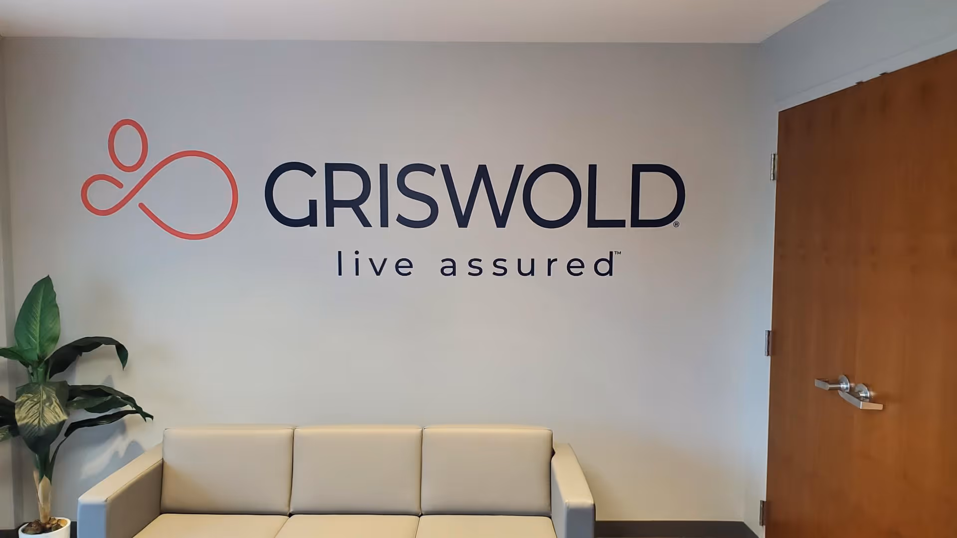 Lobby area with Griswold branding on the wall, beige sofa, and plant.