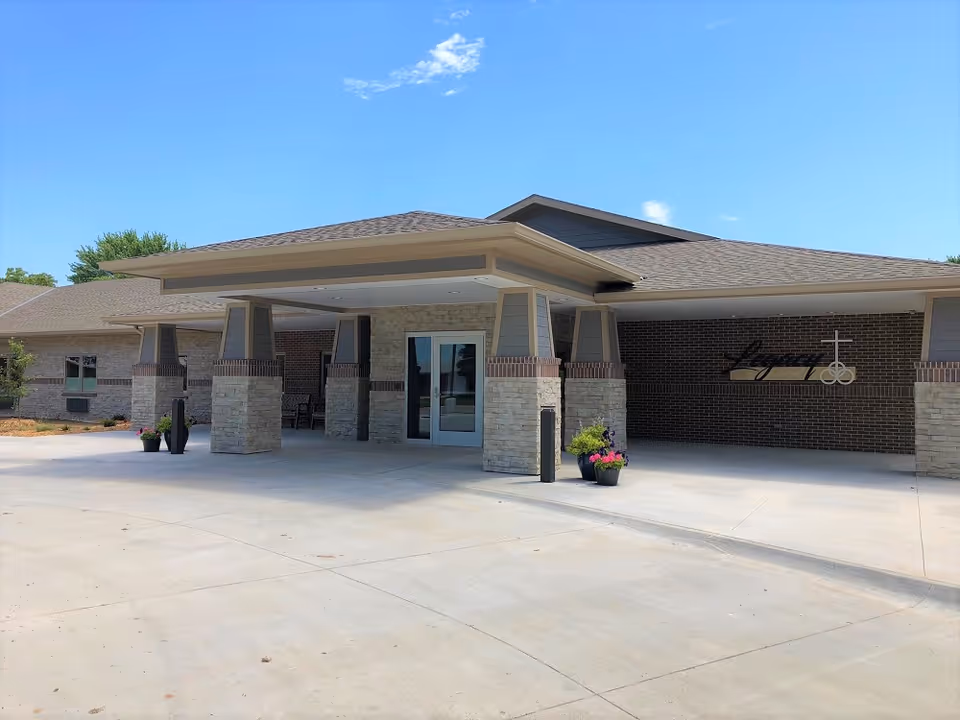 Exterior view of Legacy Square Long Term Living entrance with brick walls and stone pillars.
