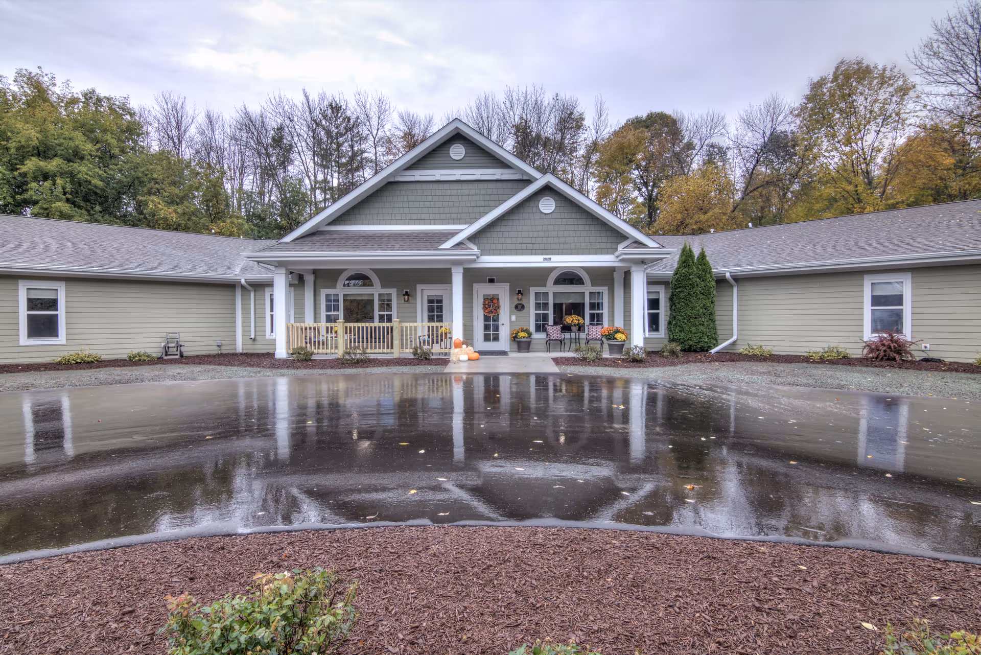 Exterior view of Retirement Inn front entrance with autumn trees and decorations.