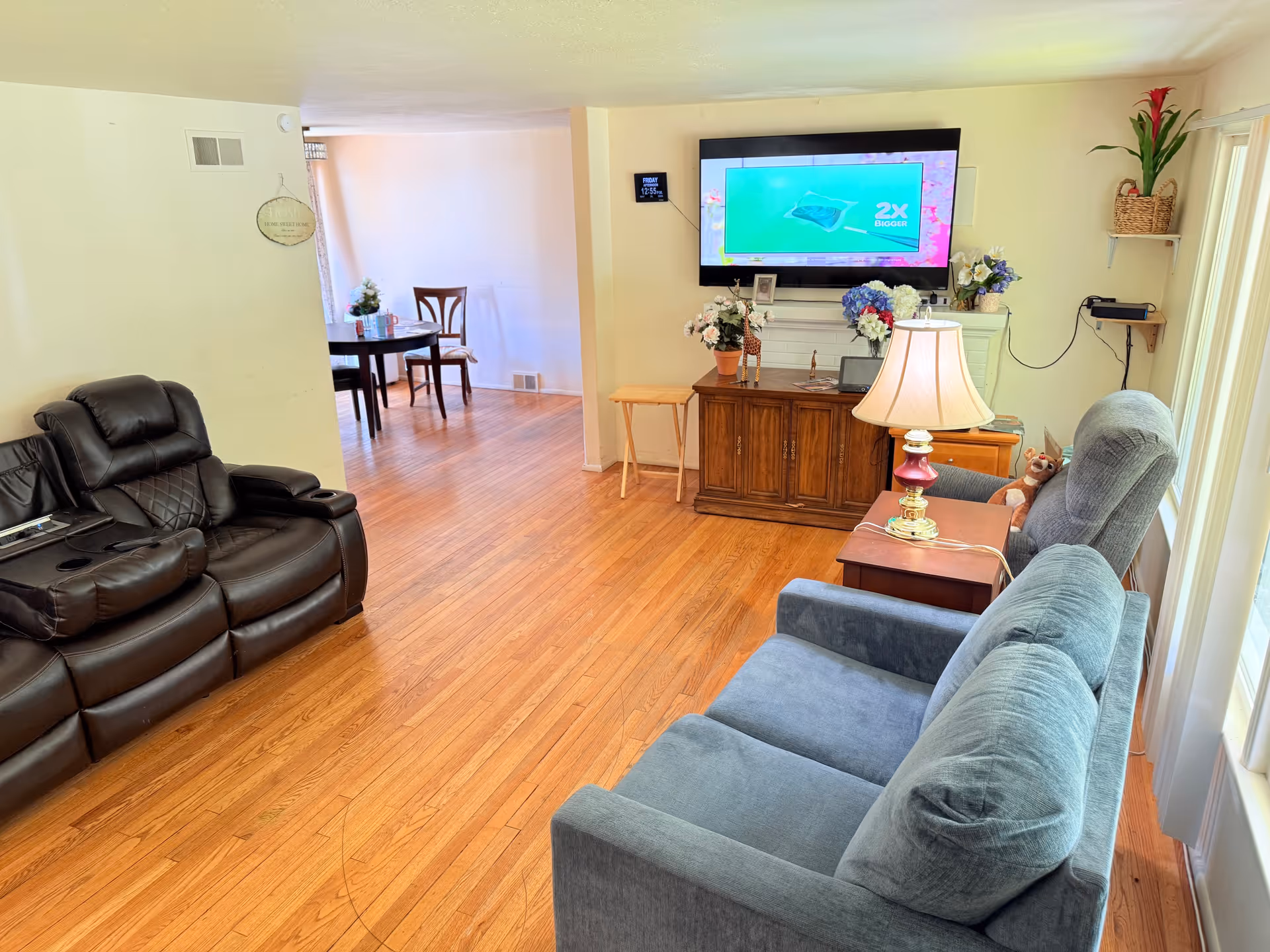 Cozy living room with blue sofa, leather recliner, TV, and floral decor.