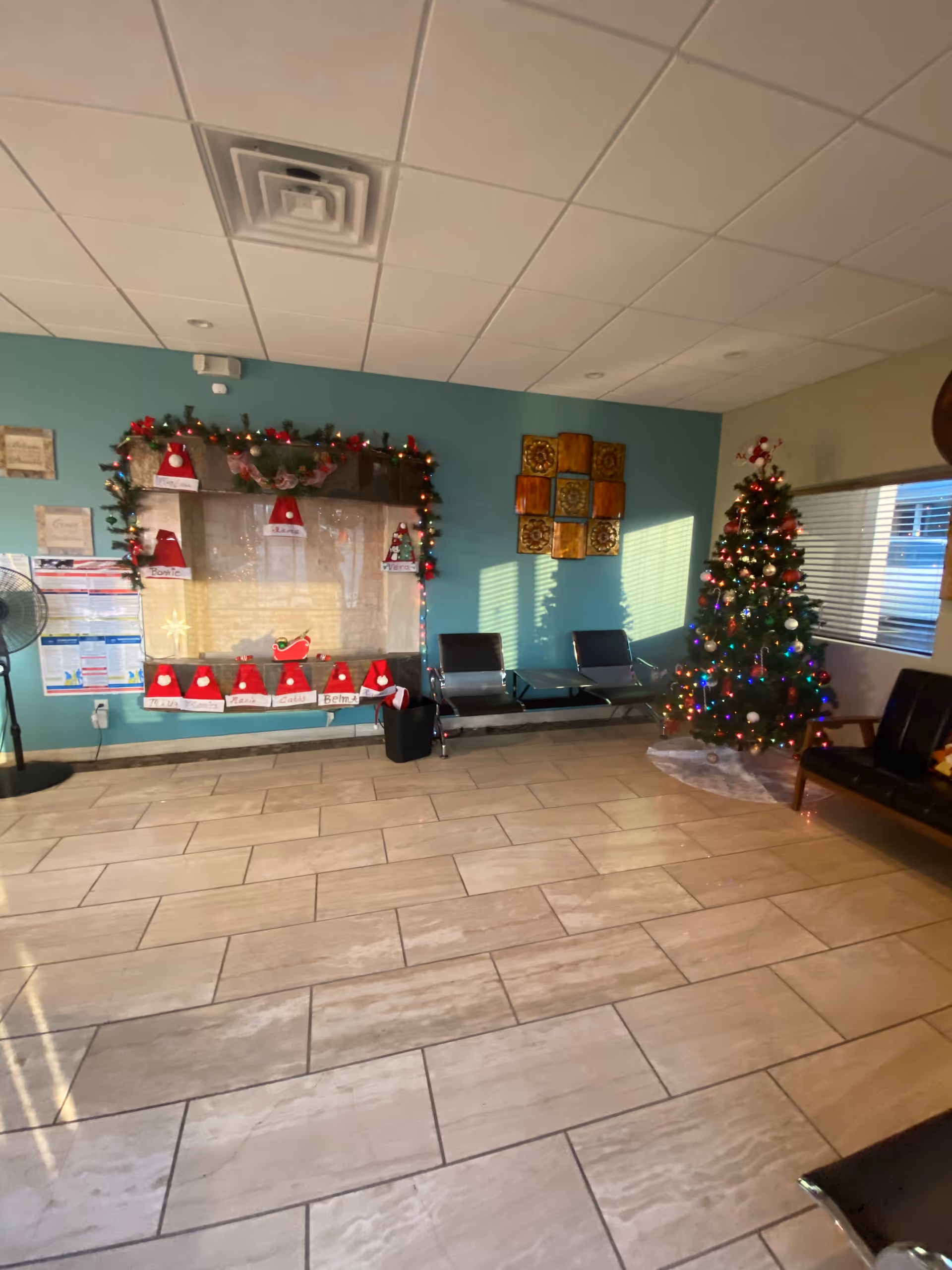 Interior lobby with holiday decorations, a Christmas tree, garlands, and row of chairs.