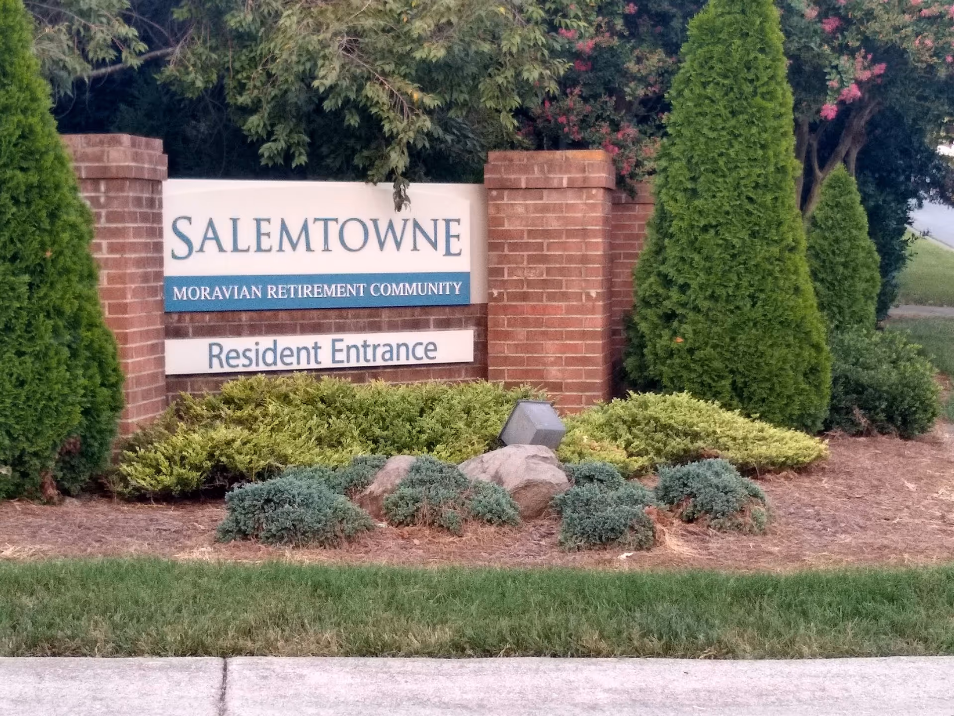 Salemtowne retirement community entrance sign, flanked by brick pillars and shrubs.