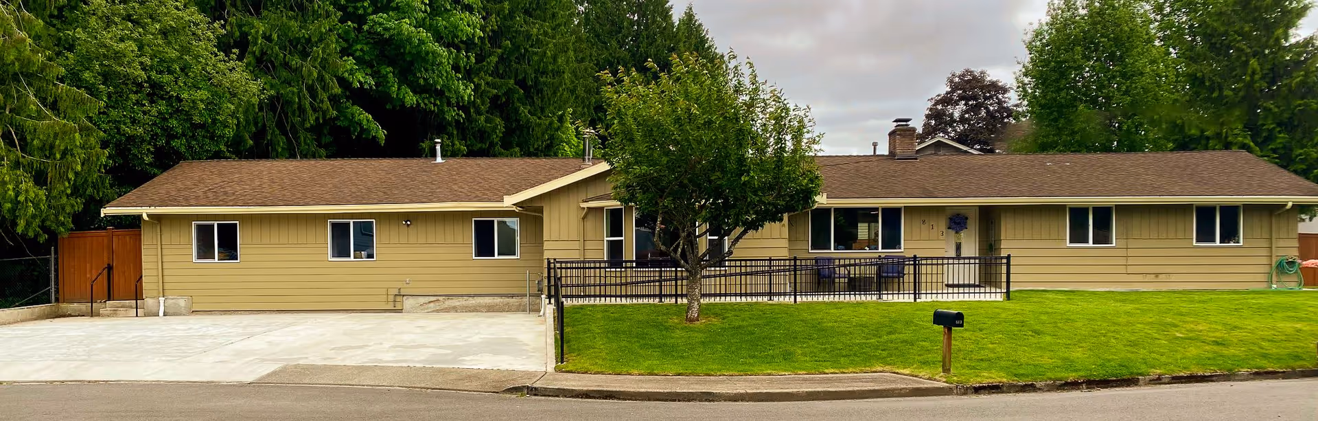 Front view of a single-story beige senior living facility with a green lawn.