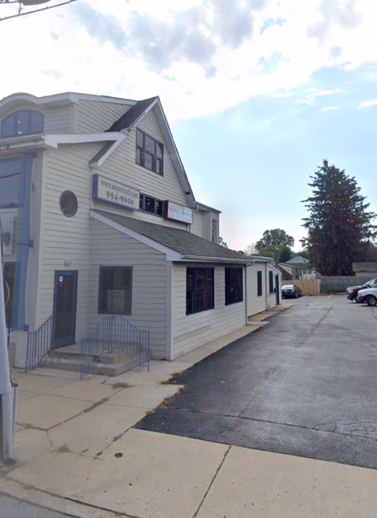 This is a two-story light-gray building with signs and a parking lot.