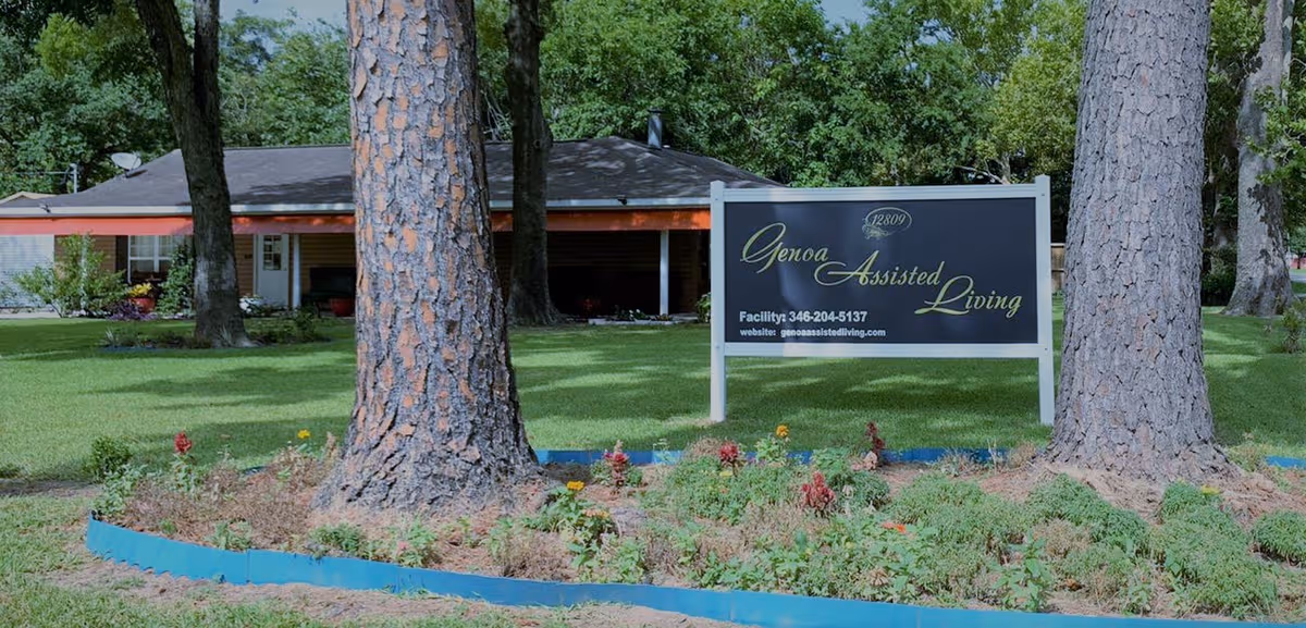 Genoa Assisted Living sign on front lawn with building and trees behind.